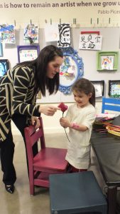 Little girl handing mom a paper rose in our Art Studio