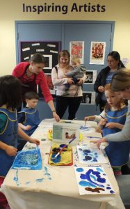 Adults and children working on watercolor paintings together in our Art Studio